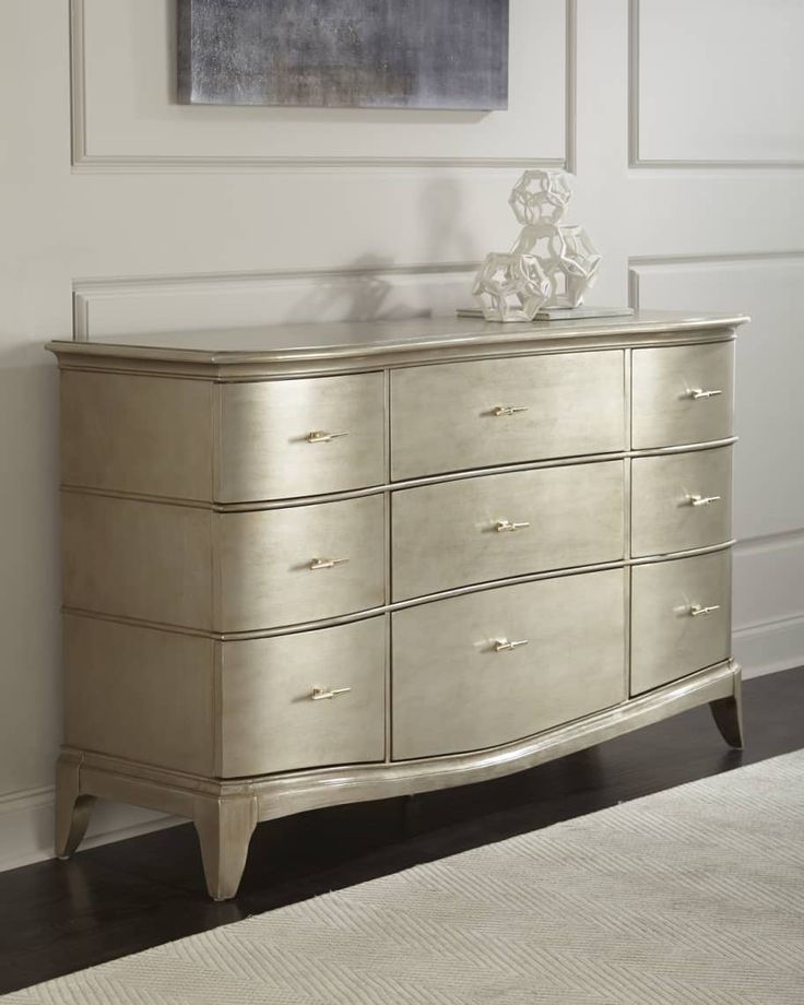 a white and gold dresser sitting next to a painting on the wall in a room