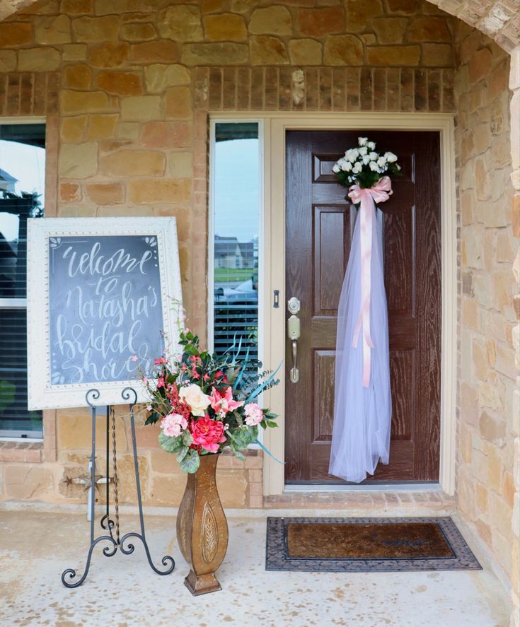 a welcome sign next to a vase with flowers on it and a chalkboard in front of the door