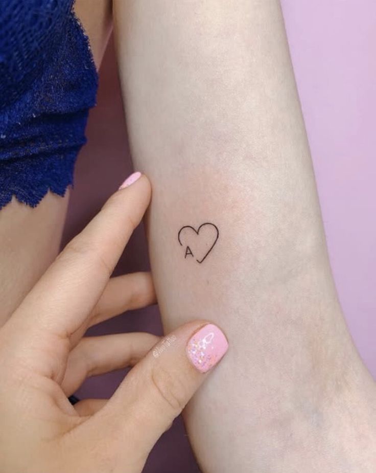 a woman's arm with a small heart tattoo on the left side of her arm