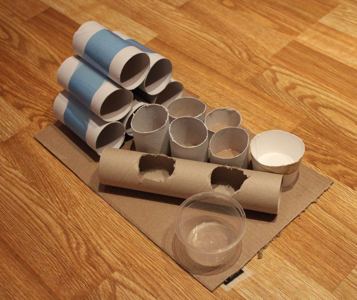 several rolled up toilet paper sitting on top of a wooden floor next to empty cups