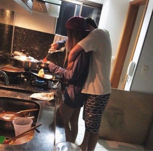 two people standing in a kitchen preparing food on top of a wooden stove burner