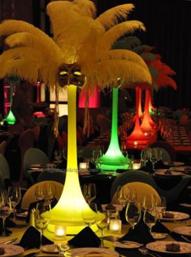 the table is set with several glasses and place settings in front of an illuminated palm tree