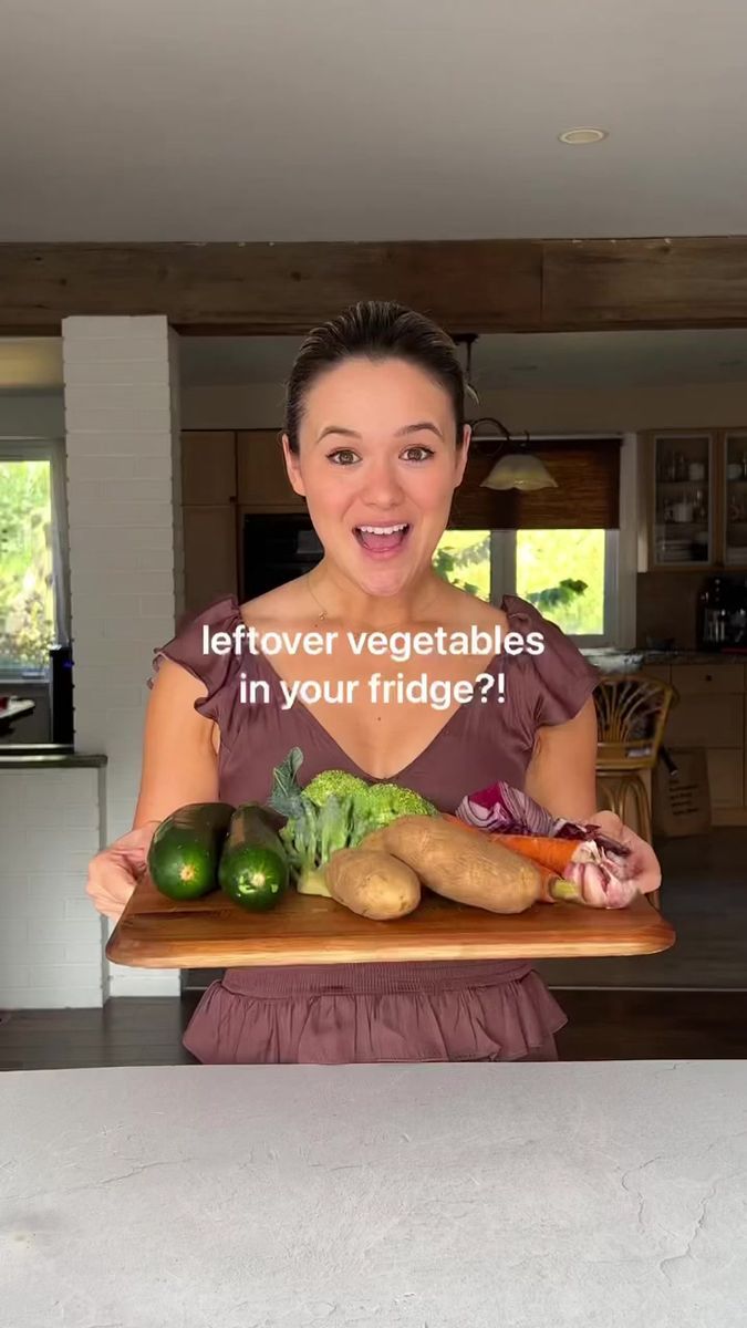 a woman holding a tray with vegetables on it