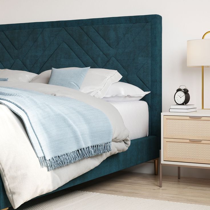 a bed with blue headboard and white sheets in a bedroom next to a night stand