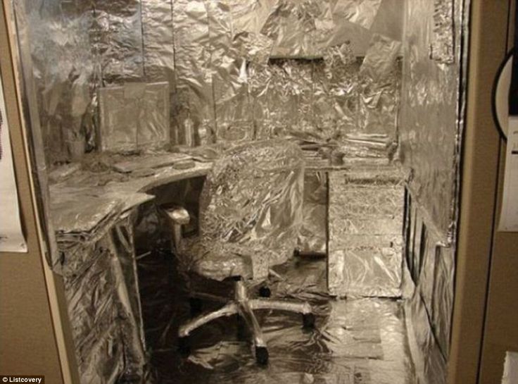 an office cubicle is wrapped in aluminum foil and has a computer desk on the other side