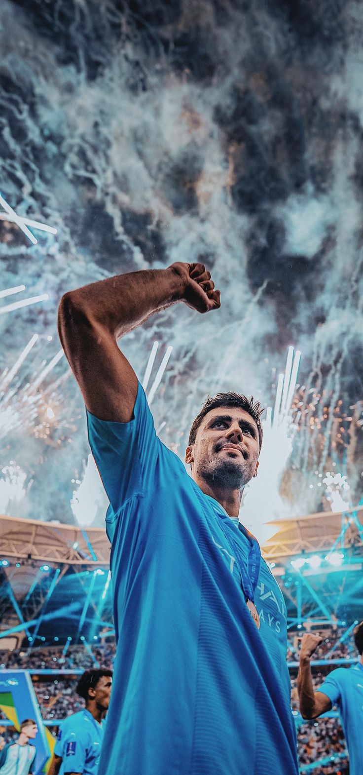 a man holding his fist up in the air while watching fireworks go off behind him