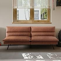 a living room with a brown couch and two windows in the wall, along with a rug on the floor