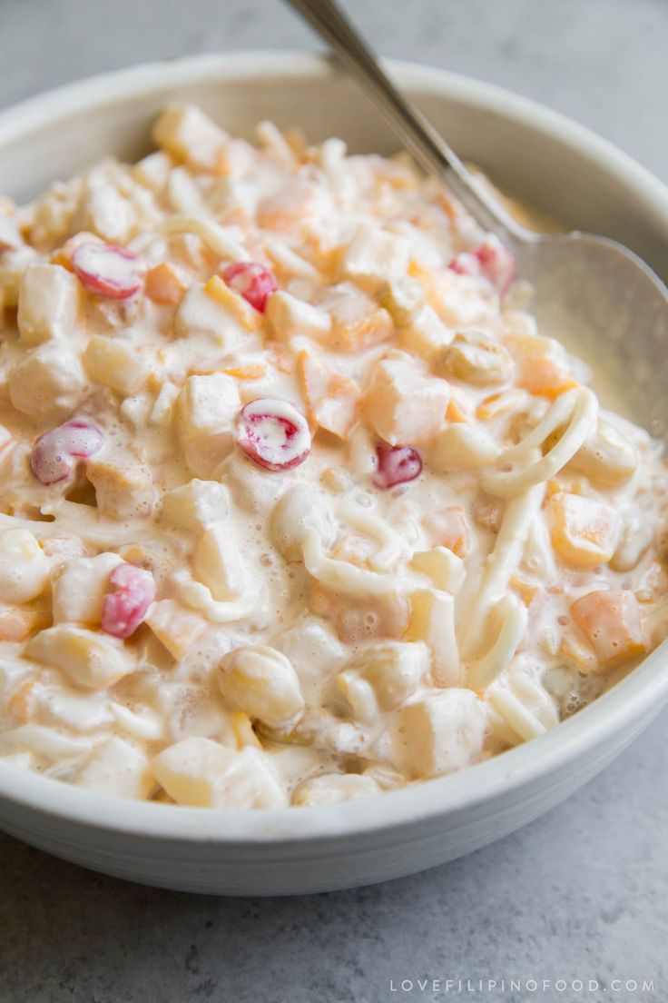 a white bowl filled with macaroni salad on top of a gray countertop