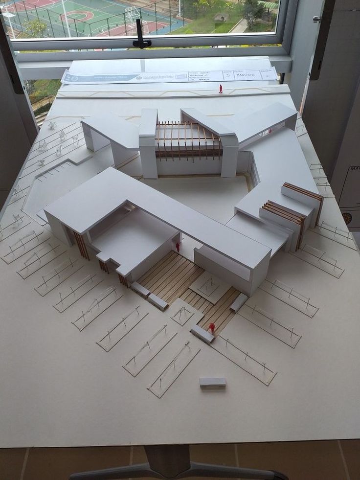 an architectural model of a building on top of a table next to a large window