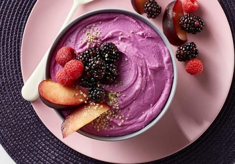 a pink plate topped with a bowl of fruit