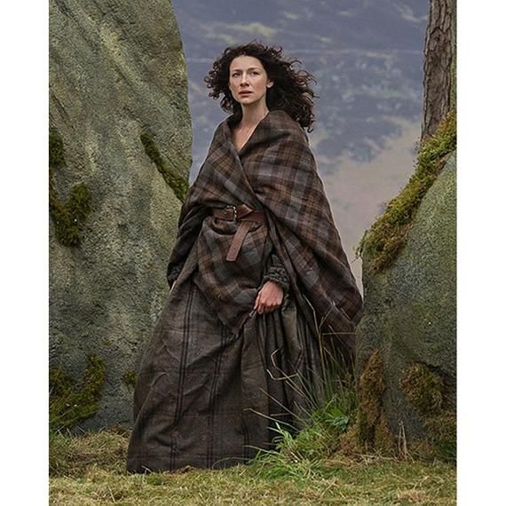 a woman in a long dress standing next to large rocks