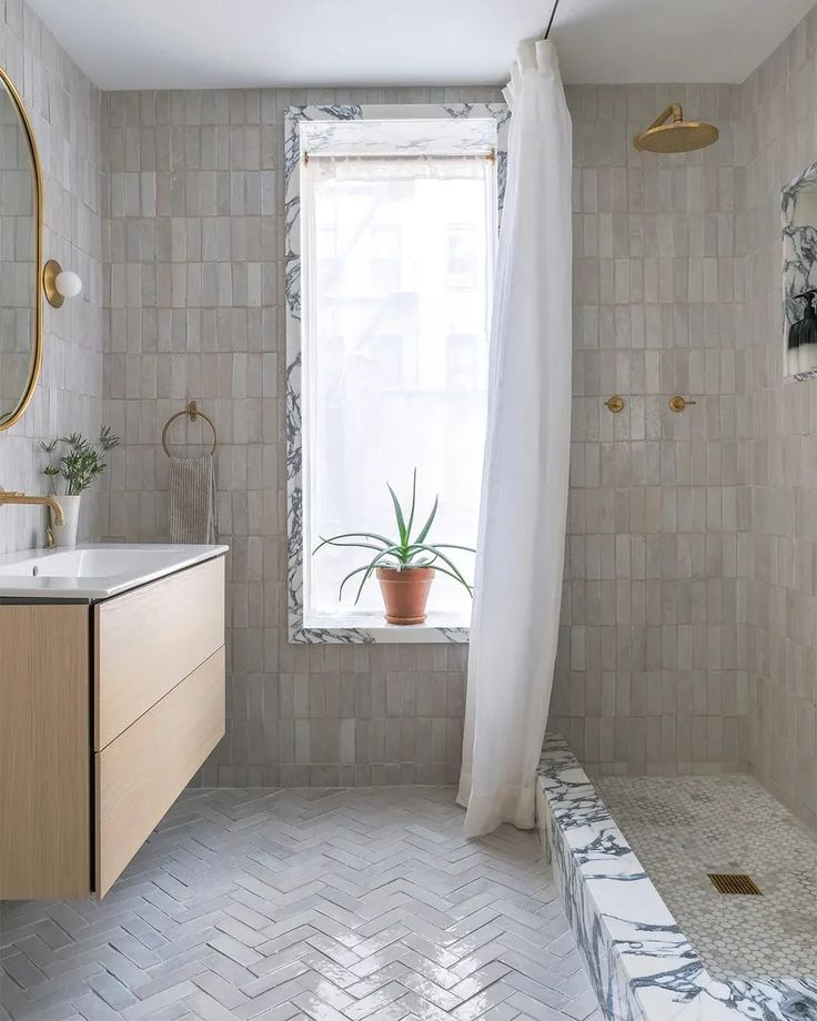 a bathroom with a tub, sink and shower in it's corner next to a window