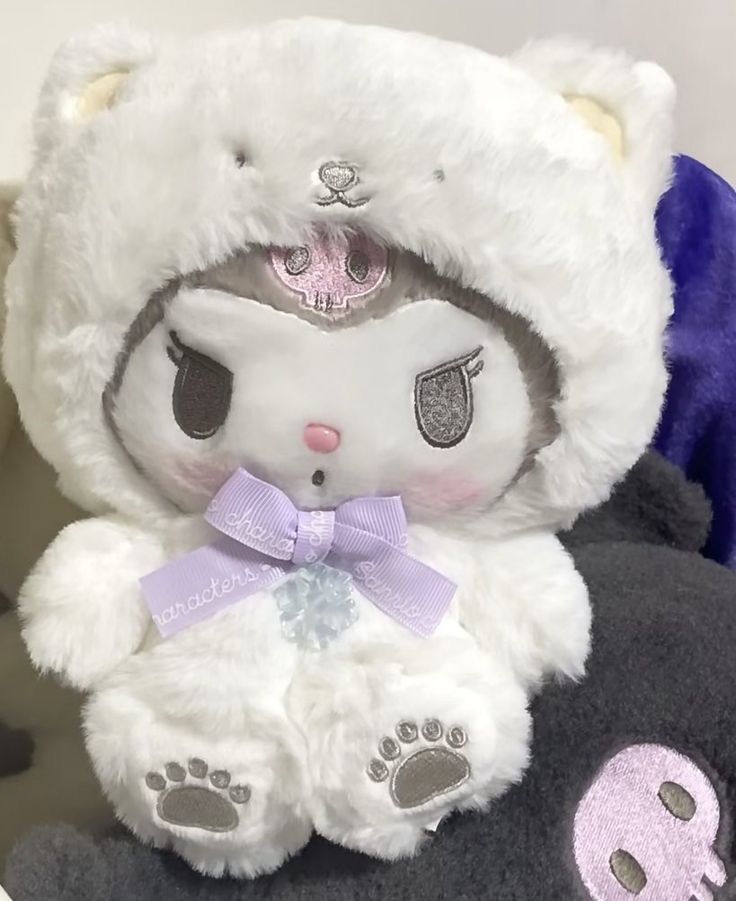 there is a white teddy bear wearing a purple bow