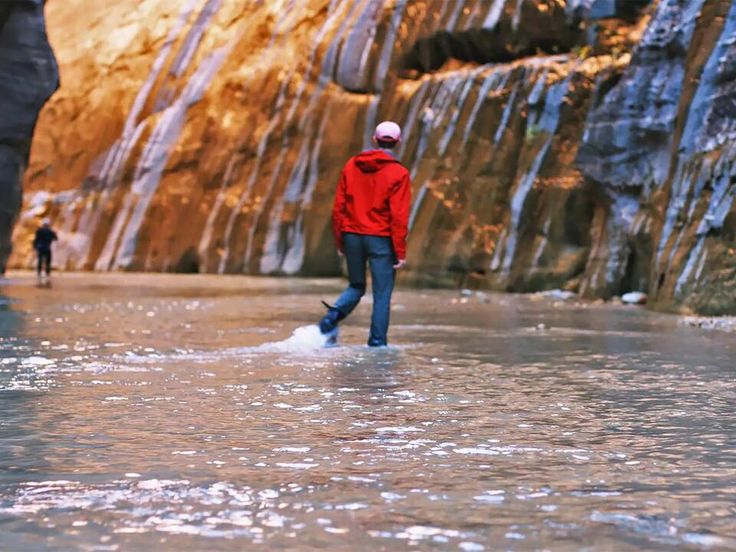 a person walking through water in front of a waterfall