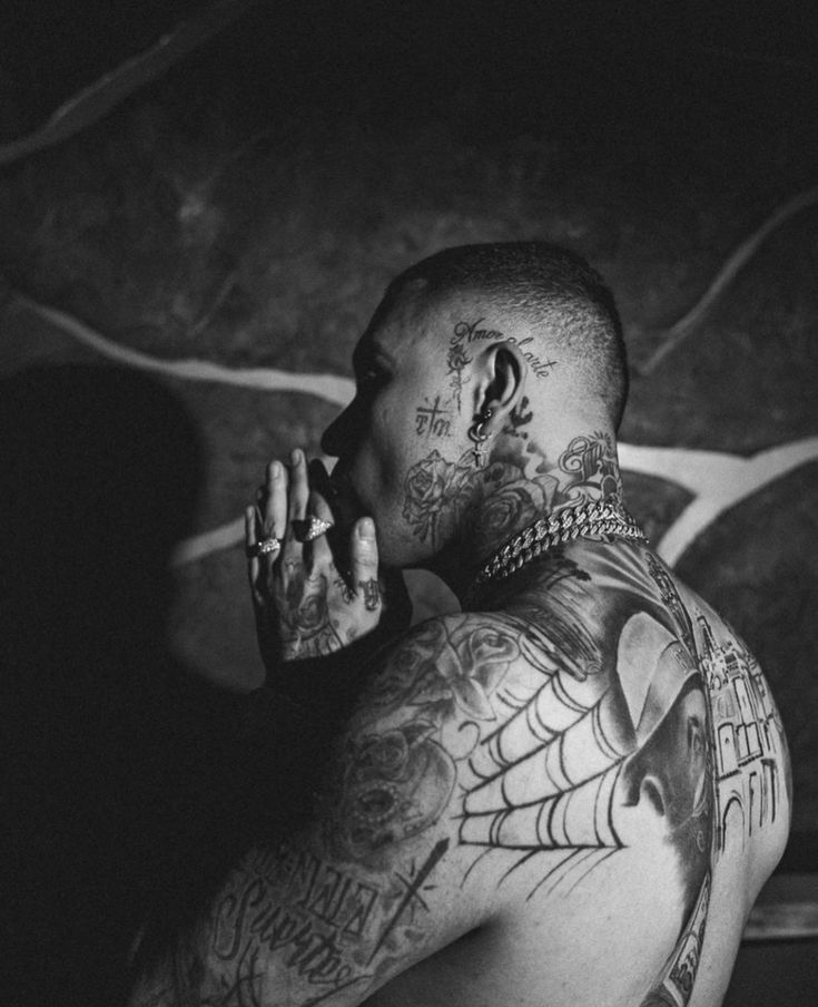 a man with lots of tattoos on his chest and hands in front of his face