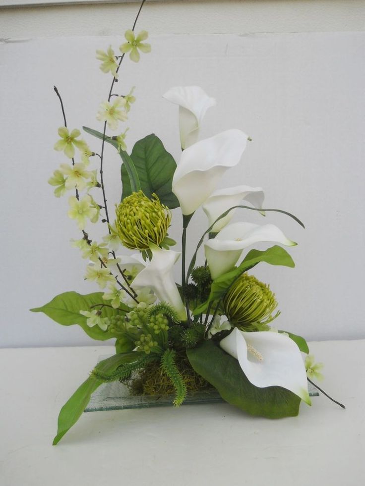 a vase filled with white flowers and greenery