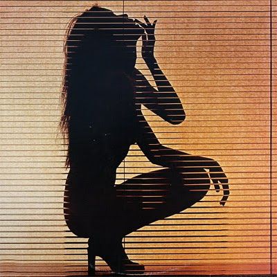 the silhouette of a woman sitting in front of blinds with her hands behind her head