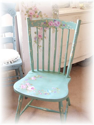 a blue chair with pink flowers painted on the back and seat is next to a white dresser