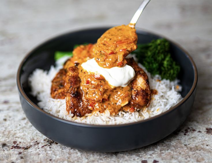 a bowl filled with rice and meat covered in sauce