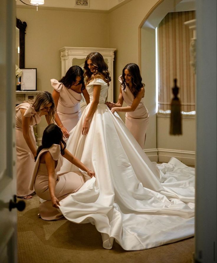 bridesmaids helping the bride put on her wedding dress