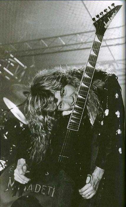 a man with long hair playing an electric guitar