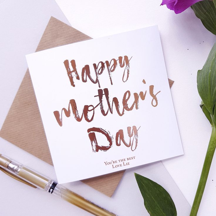 a mother's day card sitting on top of a desk next to a flower