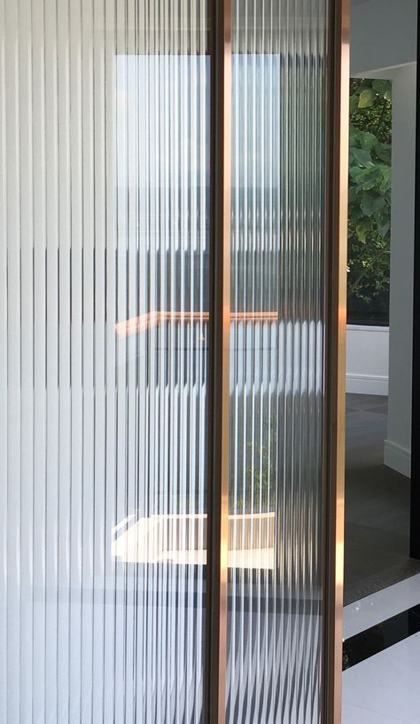 an open sliding glass door in front of a white wall and window with blinds on it