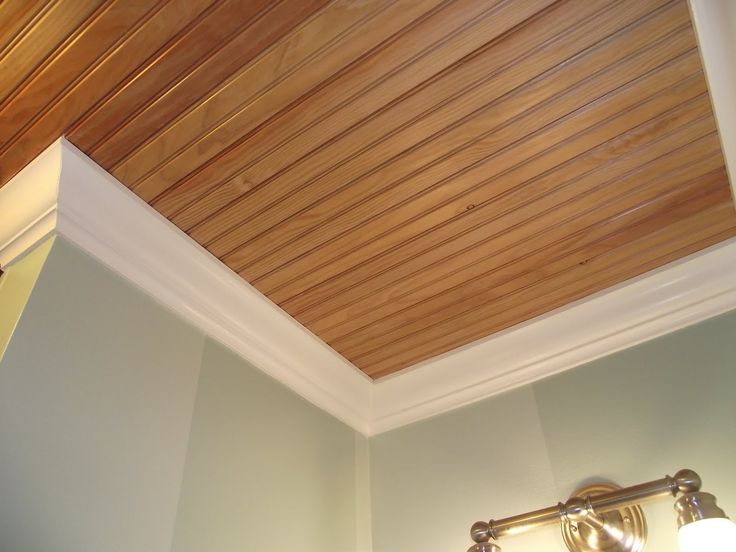 a bathroom with a sink, mirror and wooden paneling on the ceiling above it