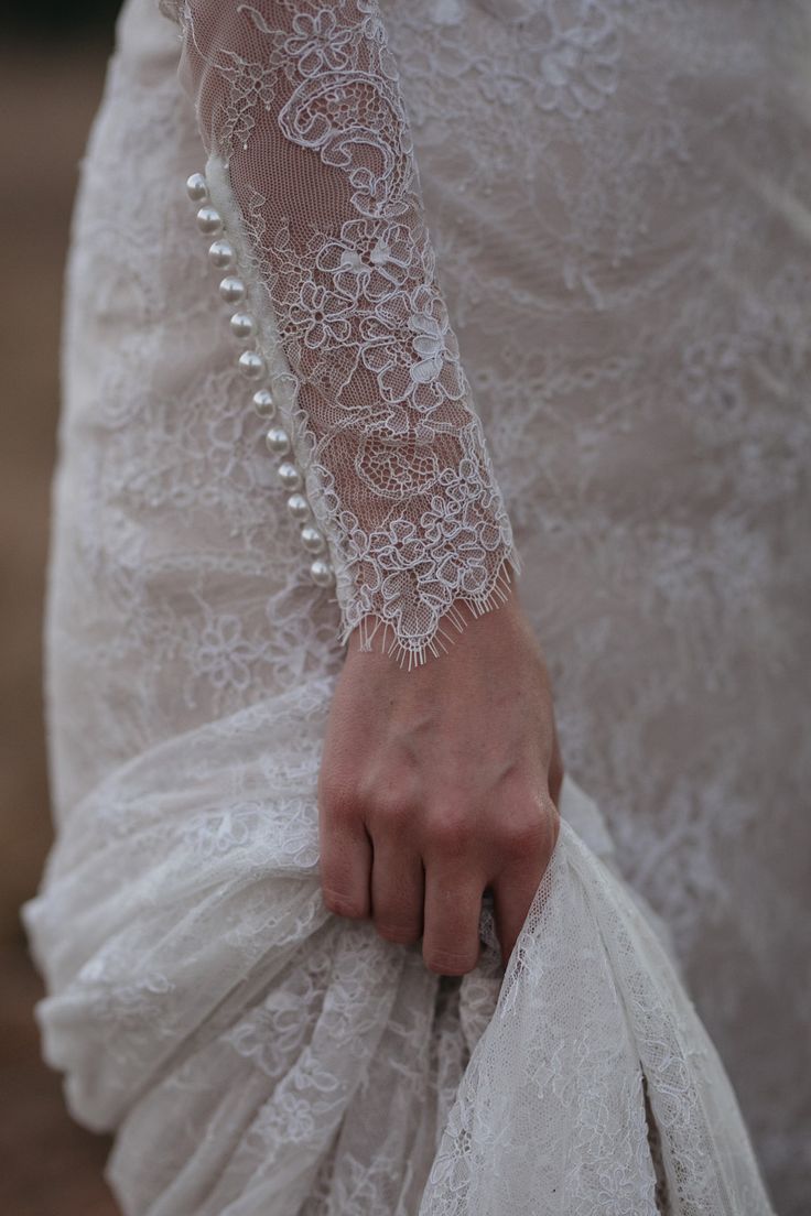 a close up of a person wearing a white dress and holding a bag with pearls on it