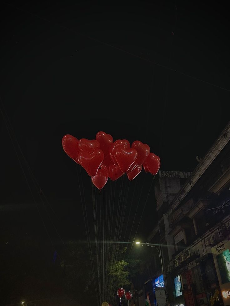 some red balloons floating in the air at night