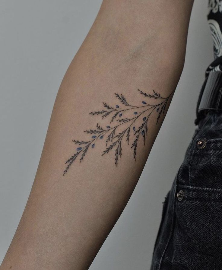 a woman's arm with a tattoo on it that has flowers and leaves growing out of it