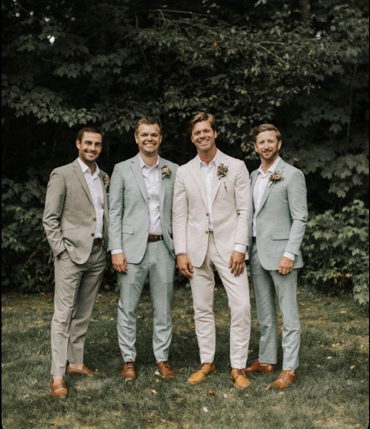 a group of men standing next to each other in front of some trees and bushes