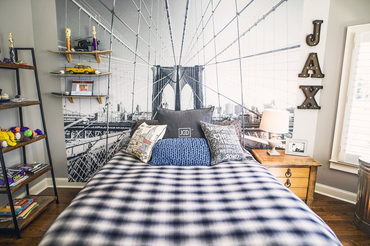 a bed room with a neatly made bed and a large mural on the wall behind it