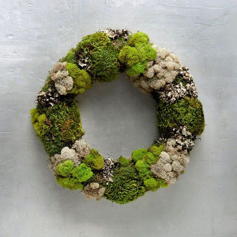 a wreath made out of moss and white flowers on a gray wall with the word love written in it