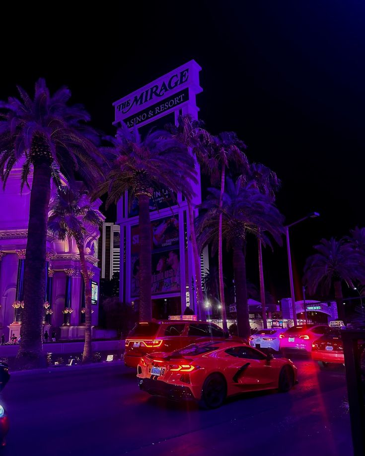 cars are parked in front of the mirage hotel and casino at night with palm trees