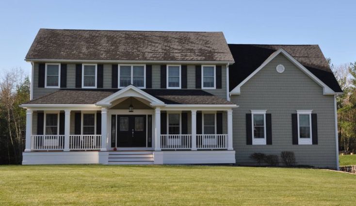 a large gray house with white trim and black shutters on the front porch is shown