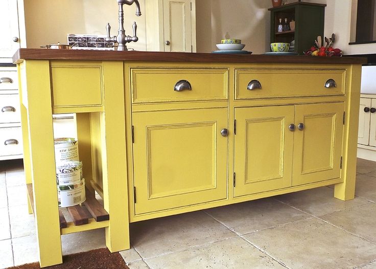 a kitchen with yellow painted cabinets and brown counter tops, in the middle of an open floor plan