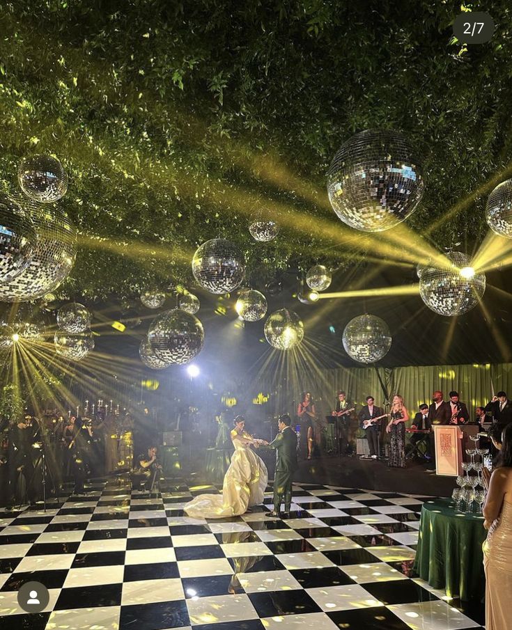 people are dancing on a checkered floor with disco balls hanging from the ceiling