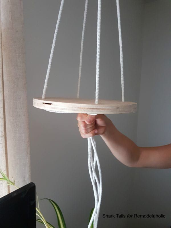 a person holding a wooden object in the air with white cords hanging from it's sides