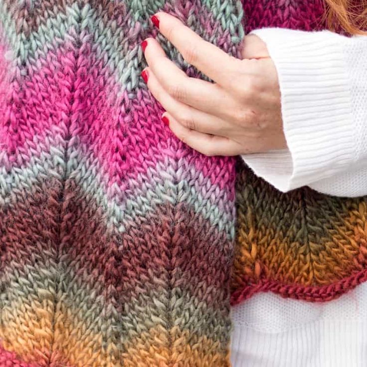 a woman's hand on the back of a colorful knitted sweater with stripes