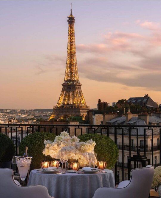 the table is set with candles and flowers in front of the eiffel tower