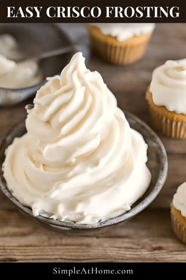 cupcakes with white frosting sitting on top of a wooden table