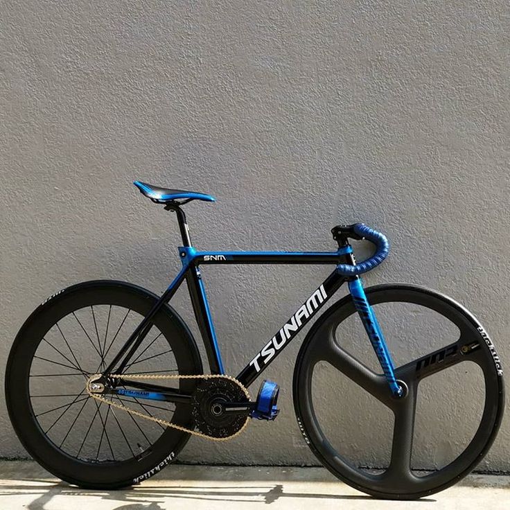 a blue and black bike leaning against a wall