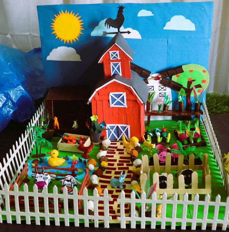 a paper farm scene is shown in front of a fence and blue sky with clouds