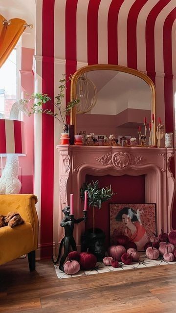 a living room filled with furniture and a fire place covered in red and white striped walls