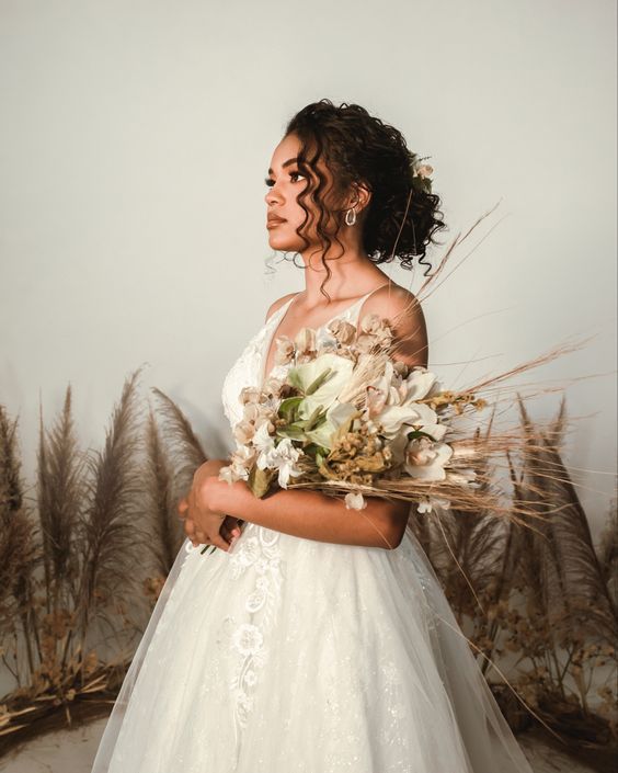 a woman in a wedding dress holding a bouquet and looking off to the side with her hand on her hip