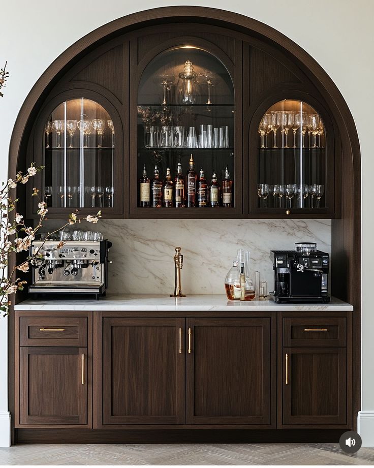 a bar with wine glasses and liquor bottles on the top shelf, next to a coffee maker