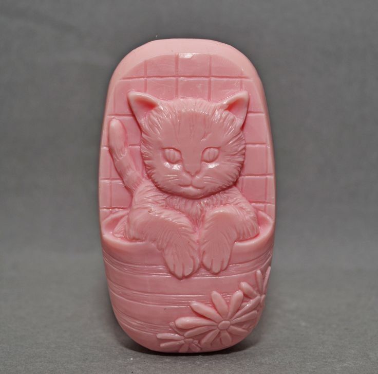 a pink cat figurine sitting on top of a flowered pot with its eyes closed