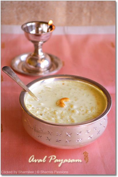 a silver bowl filled with soup next to a metal cup on top of a pink table cloth