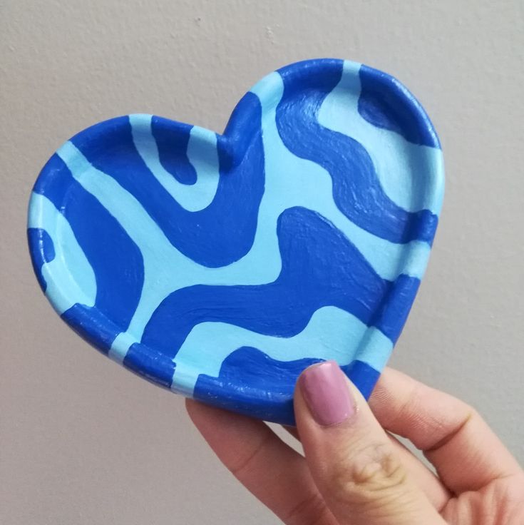 a hand holding a blue heart shaped paper plate